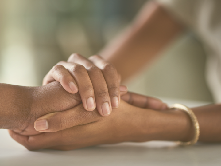 Two people clasp hands together in support.